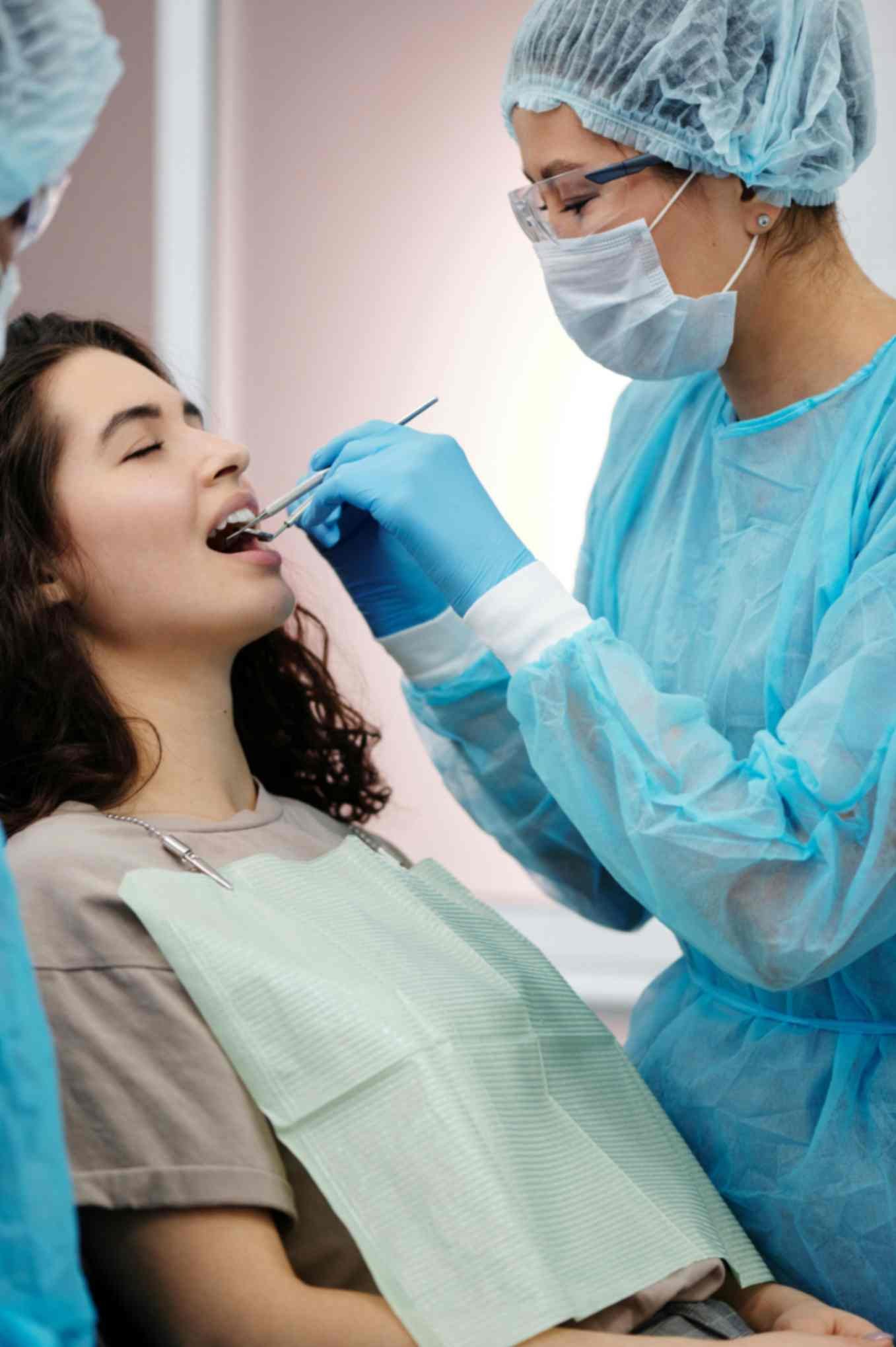 Dental professional examining patient’s teeth in a dental office, highlighting patient care and oral health services.