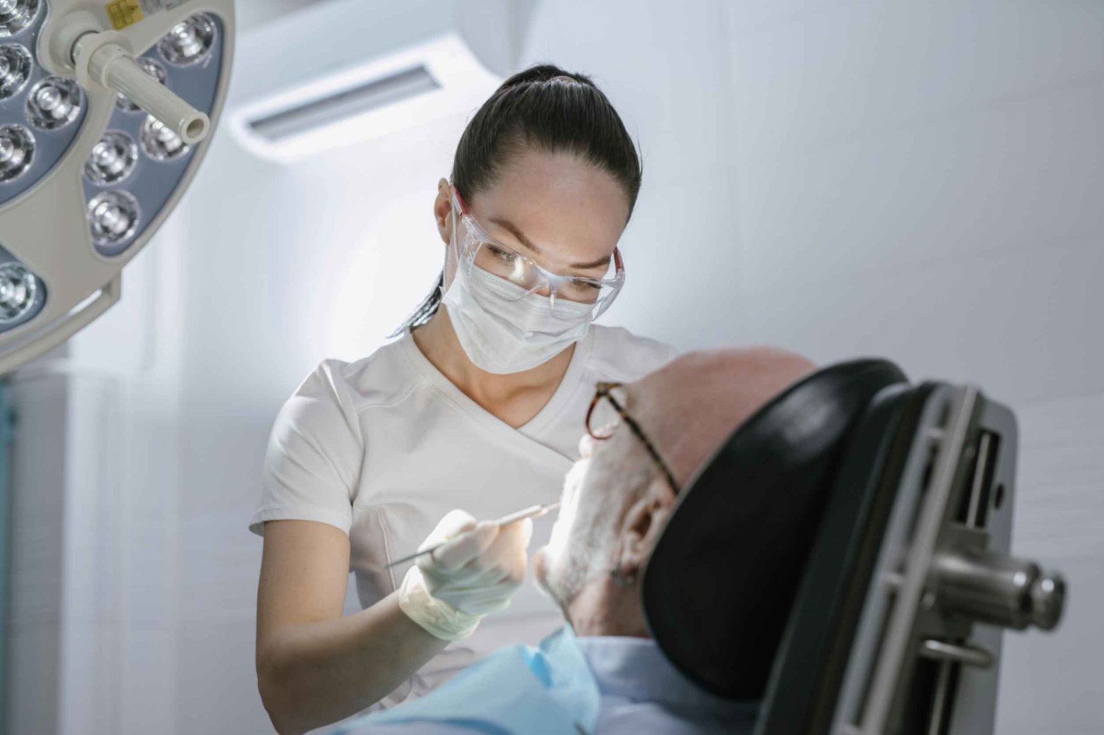 Dental professional examining patient in a clinical setting, highlighting patient care and expertise at Peak Performance Health.