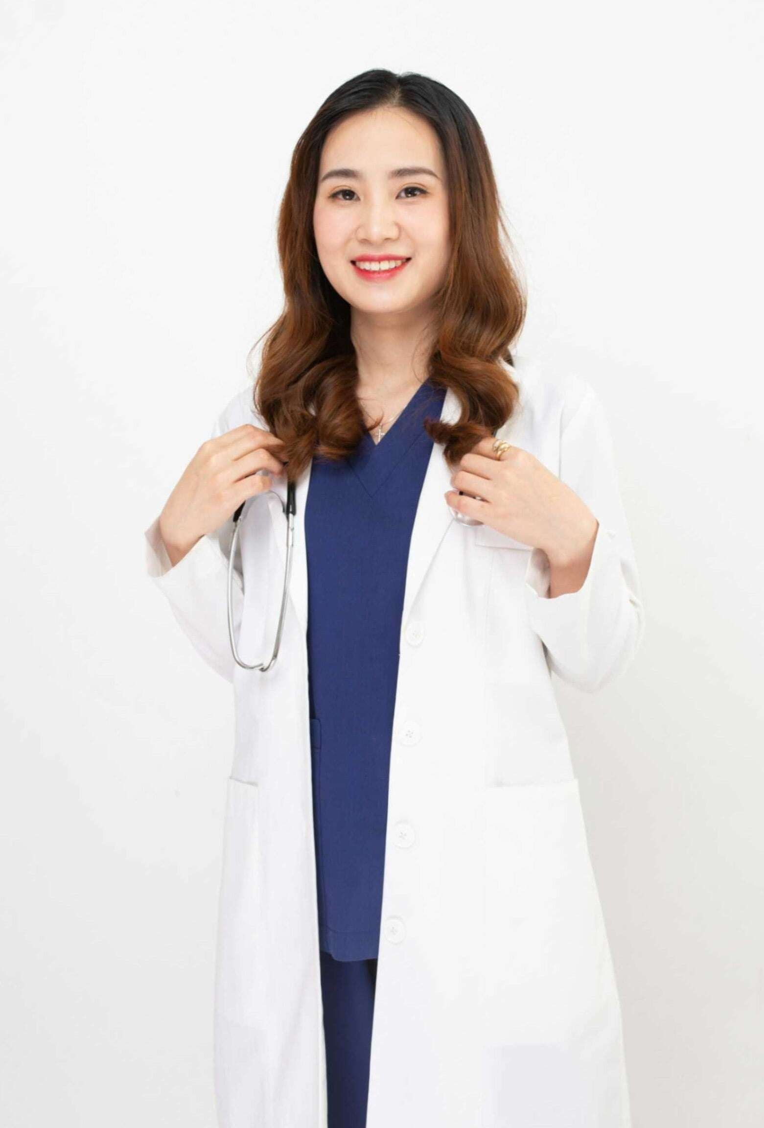 Female dentist in a white coat with a stethoscope, smiling confidently, representing the dental team at Peak Performance Health.